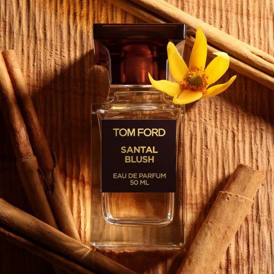 Tom ford santal blush perfume bottle with a yellow flower on a wooden surface