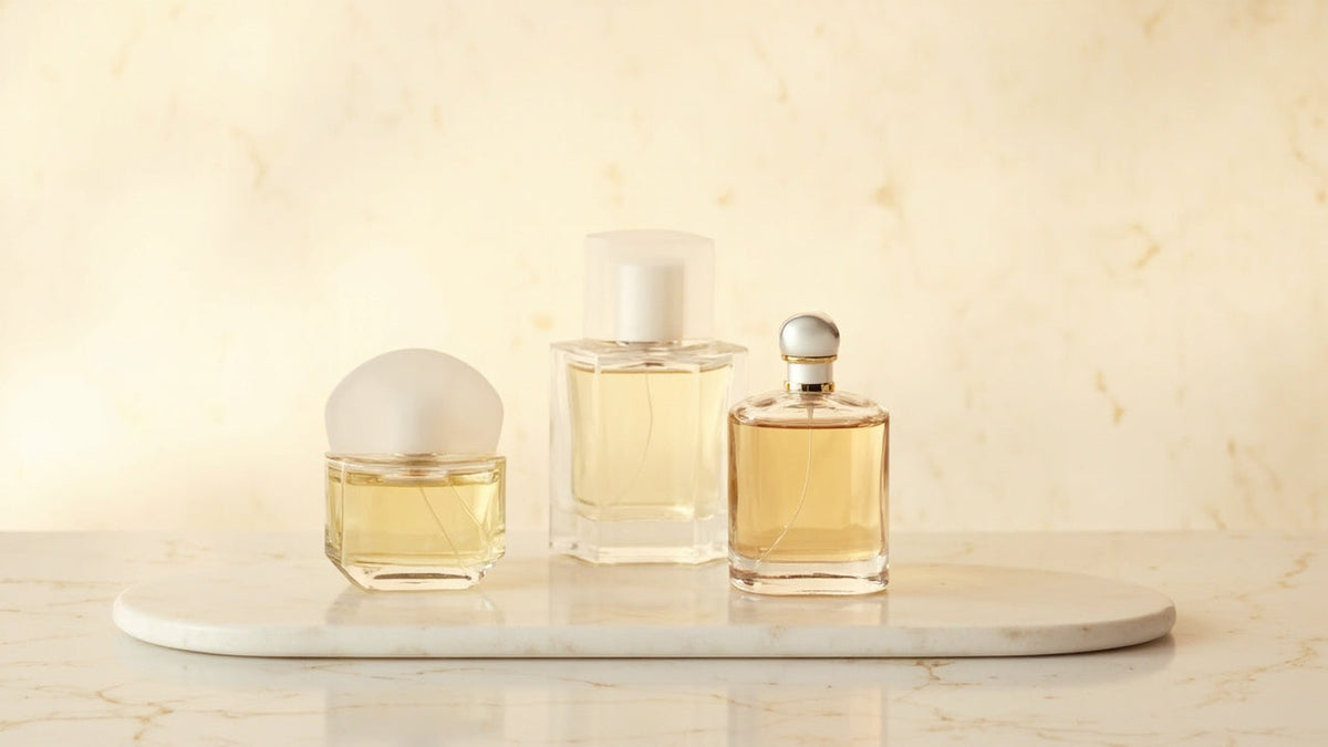 Elegant glass perfume bottles on marble with soft warm lighting and subtle reflections