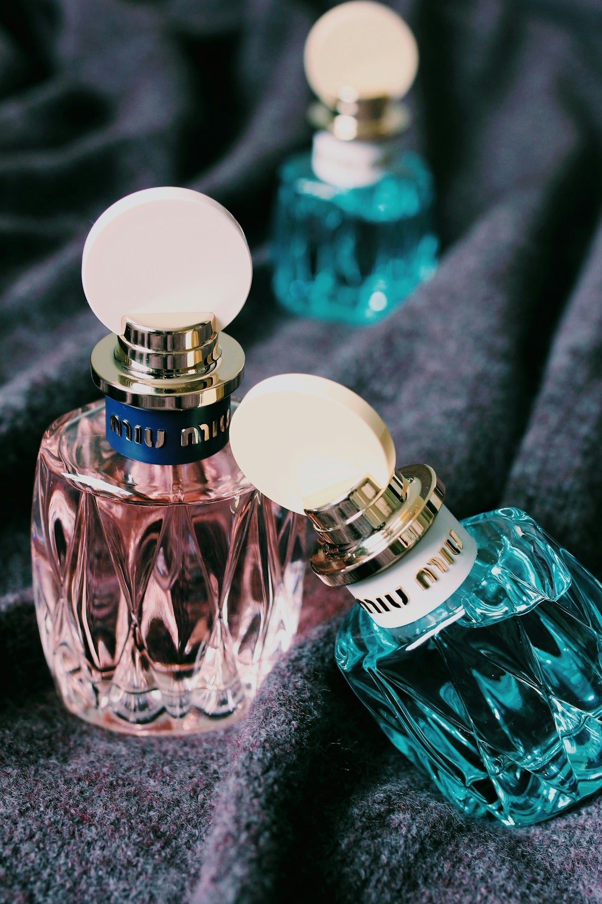 Three green and pink bottles on black textile