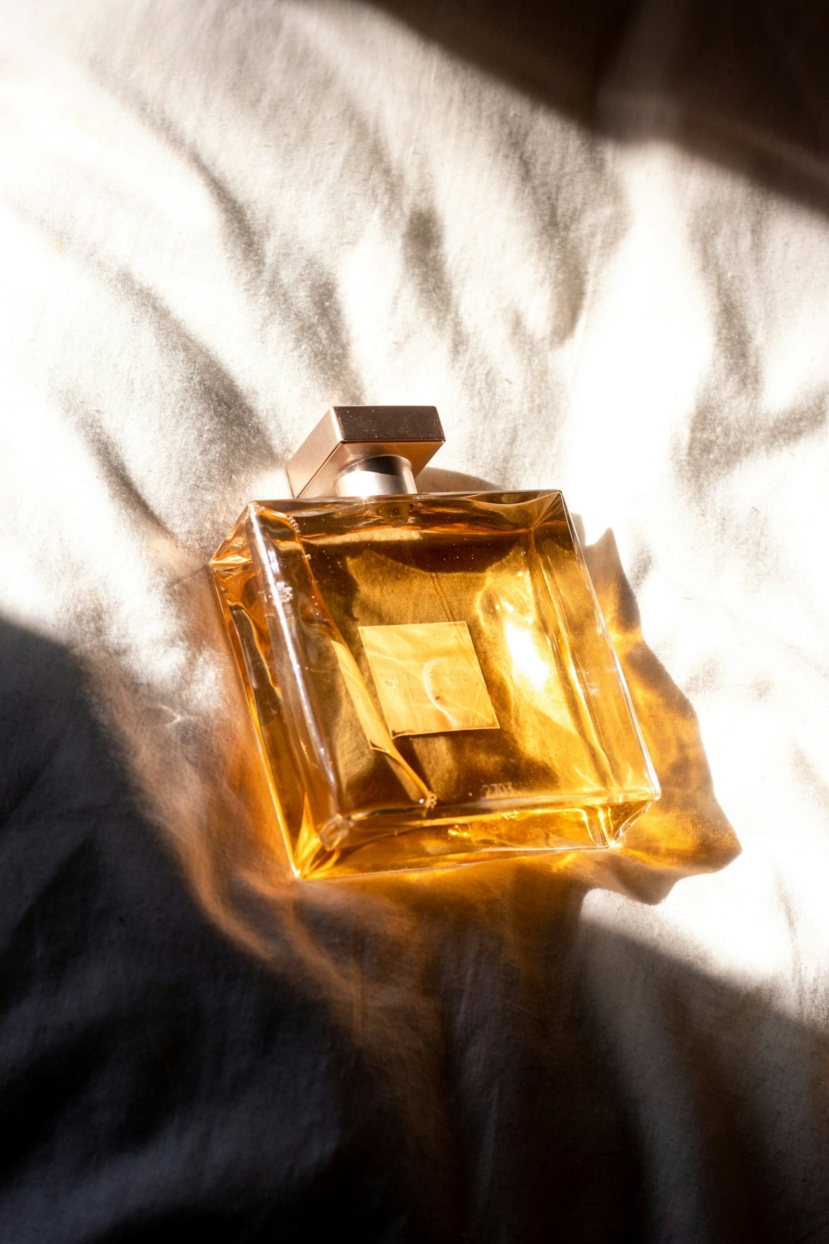 Gold perfume bottle on white textile