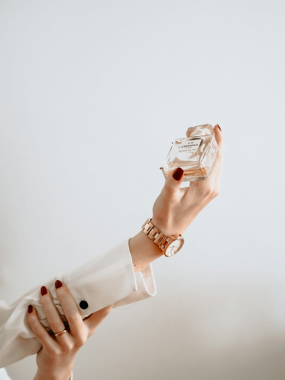 Person in white dress holding clear glass bottle