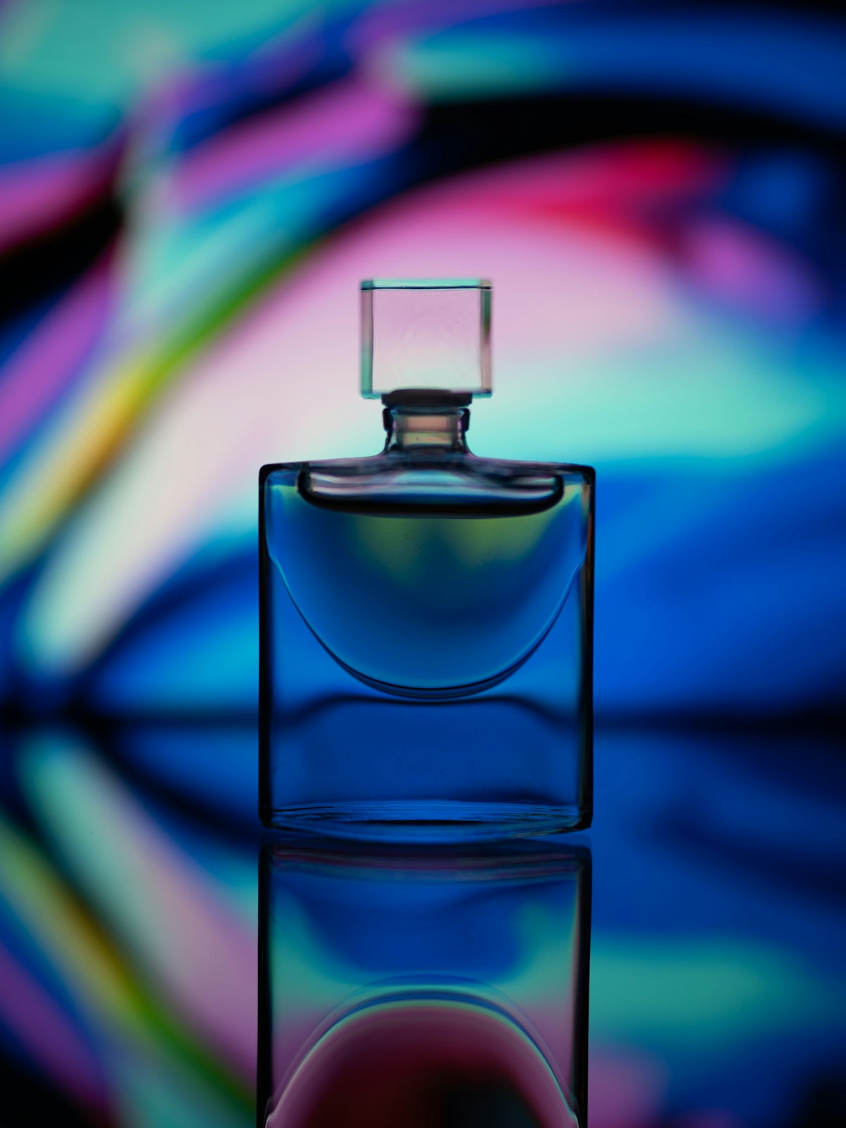 Clear glass perfume bottle with pink light