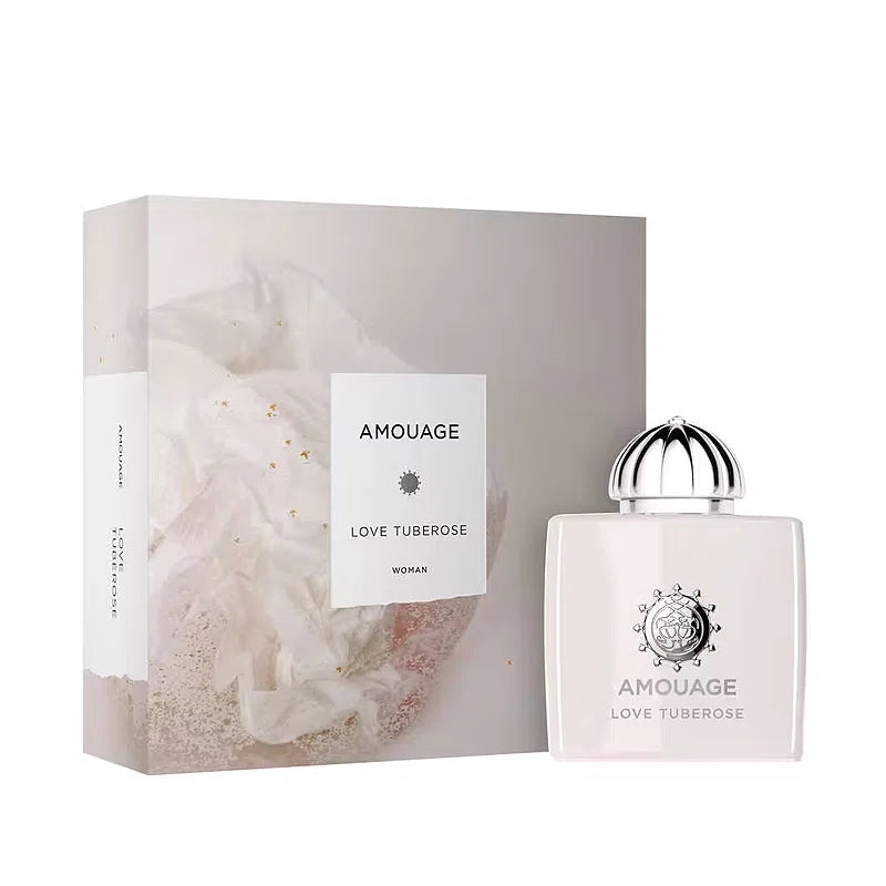 Amouage love tuberose woman perfume bottle with a silver cap next to its matching pale pink and white box, on a clean white background